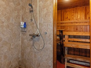 A shower area with a stone wall, wooden paneling, and a wooden bench.