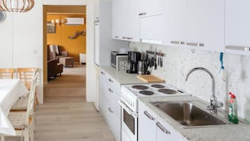Uma cozinha moderna com armários brancos, uma pia de aço inoxidável e um fogão embutido.