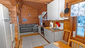 Une cuisine compacte aux murs en bois, avec une table à manger et un canapé dans le salon attenant.