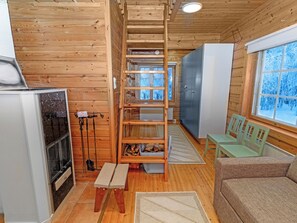 A cabin interior with a wooden interior, a fireplace, a dining table, and a sofa. - Pohjaslahdentie 17 a by Interhome (Kuusamo)
