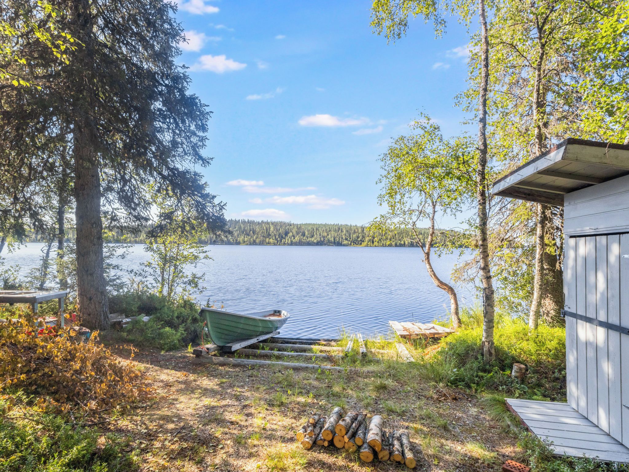 A lakeside cabin with a dock, surrounded by trees and a calm lake.
