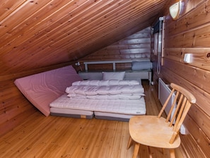 A small, cozy attic bedroom with a sloped ceiling, a single bed, a chair, and a radiator. - Pohjaslahdentie 17 b by Interhome (Kuusamo)
