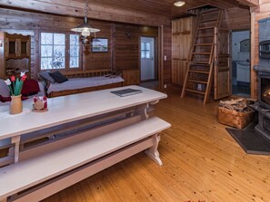 A cabin interior with a wooden bench, a table with a book, a fireplace, and a ladder. - Pohjaslahdentie 17 b by Interhome (Kuusamo)