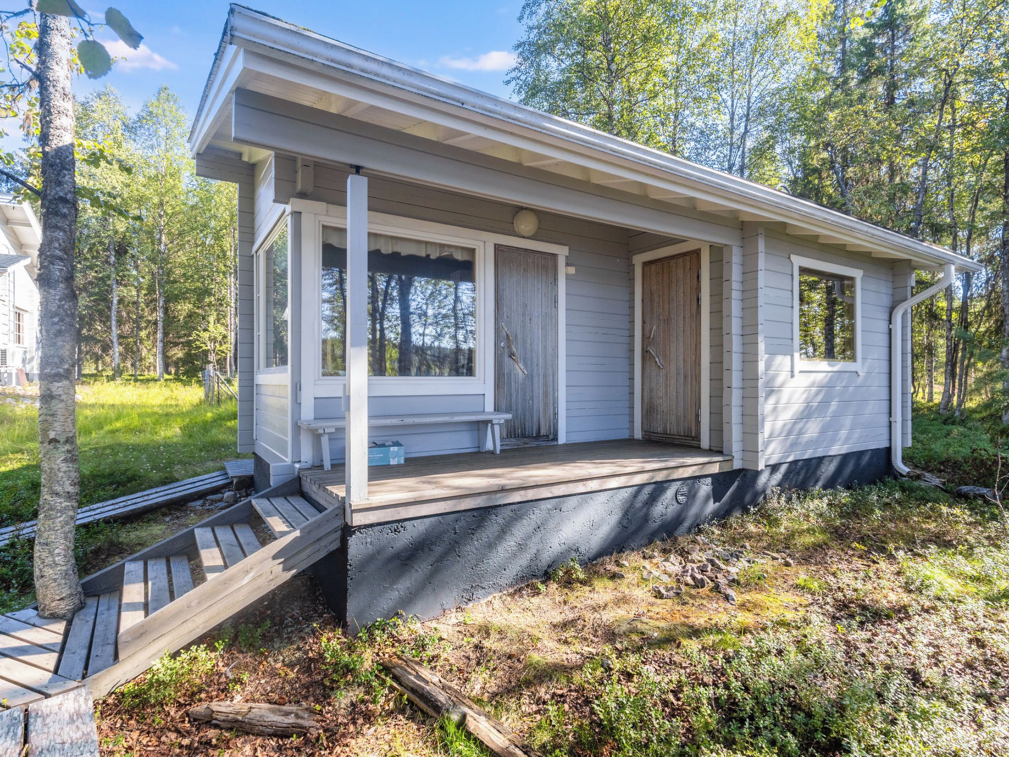 A single-story house with a porch, a front door, and a small deck area.