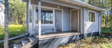 Une maison de plain-pied avec un porche, une porte d’entrée et une petite terrasse.