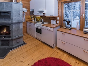 Une cuisine moderne avec une cheminée en pierre, des armoires en bois et une fenêtre donnant sur un paysage enneigé.