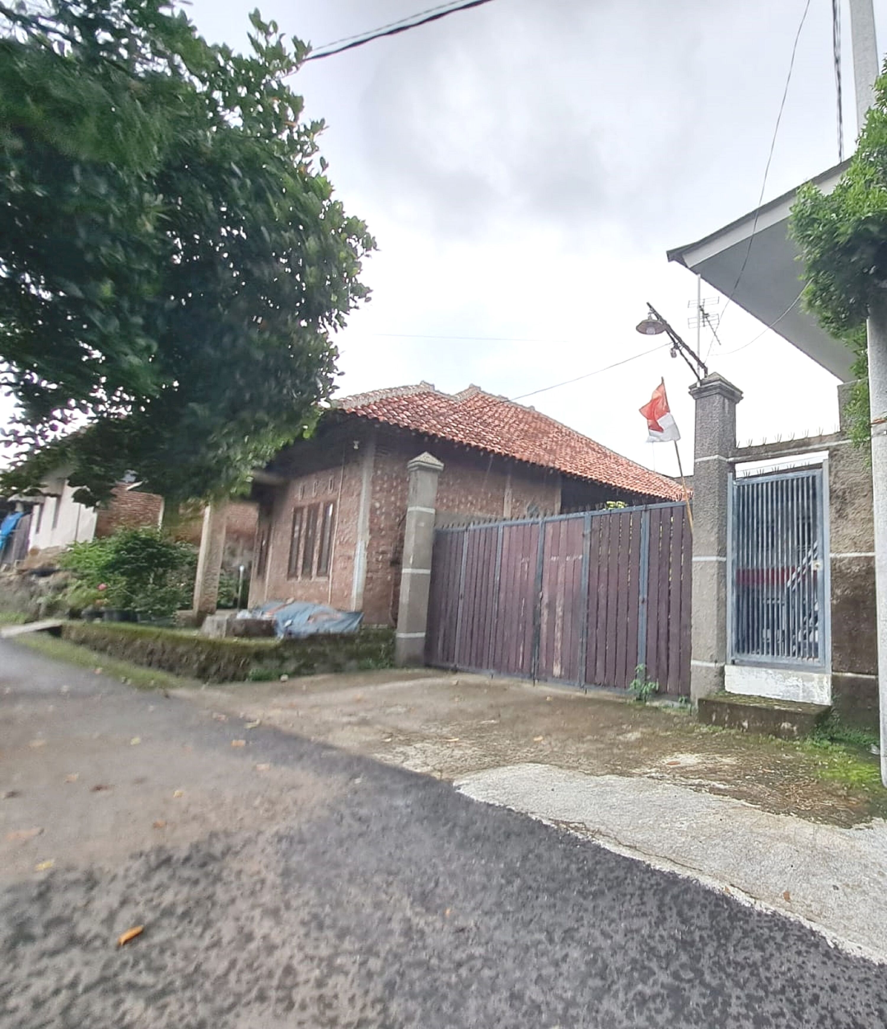 Un edificio residenziale con tetto in tegole, ingresso con cancello e un piccolo giardino.