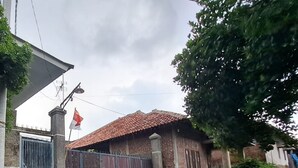 A residential house with a gated entrance, a tiled roof, and a flag on a pole. - OYO LIFE 93634 Penginapan D'palinggihan Syariah (Sumber)