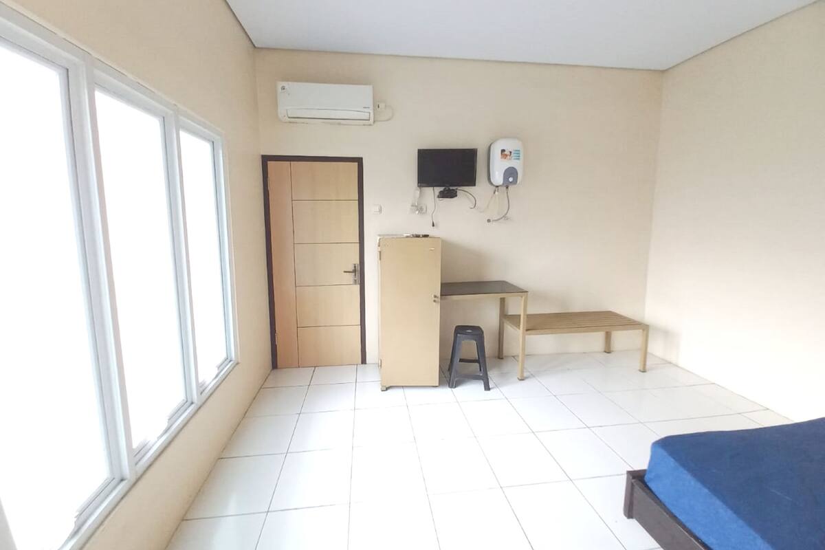 A room with a bed, a desk, a chair, a wardrobe, a window, and an air conditioning unit.