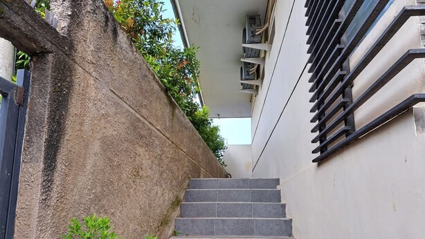 A staircase leading up to a building with a stone wall on one side and a metal railing on the other. - OYO LIFE 93634 Penginapan D'palinggihan Syariah (Sumber)