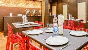 A restaurant with tables set for dining, a counter with a menu, and a patterned wall. - Navaratna Delight (Coimbatore)