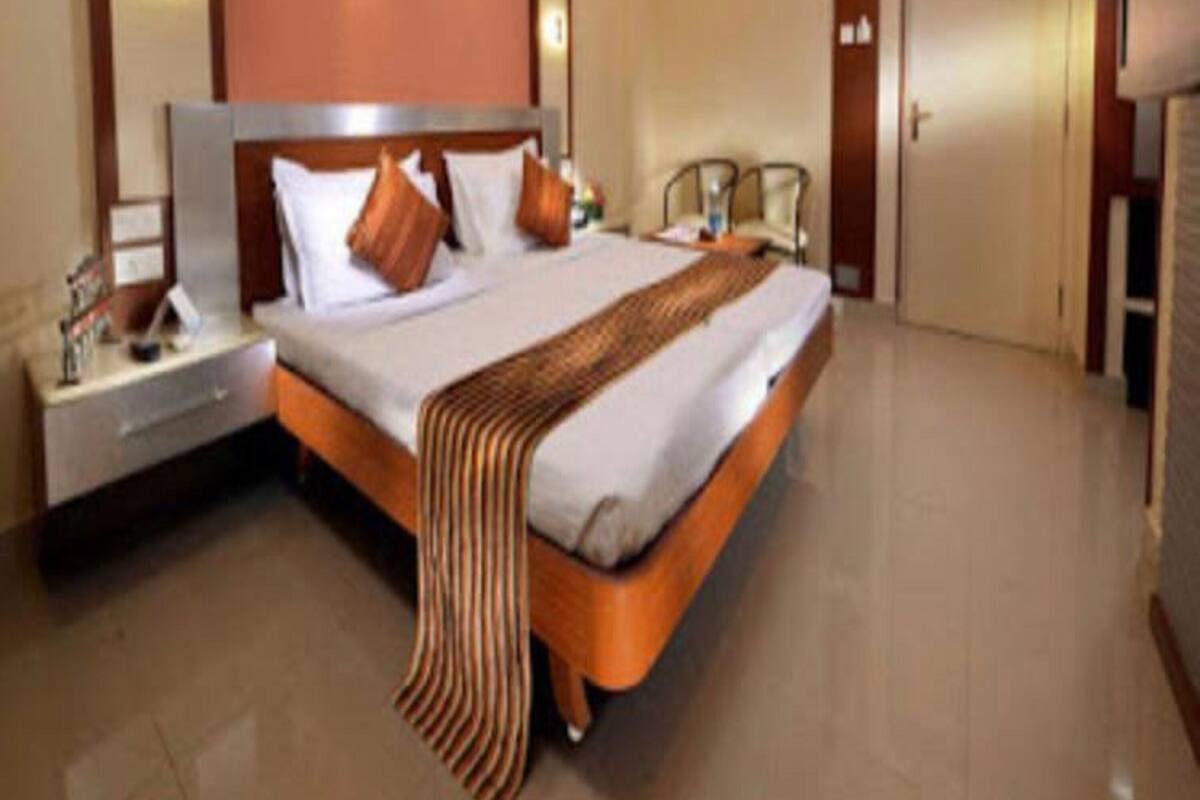 A hotel room with a large bed, a nightstand, a bedside table, a chair, and a door.
