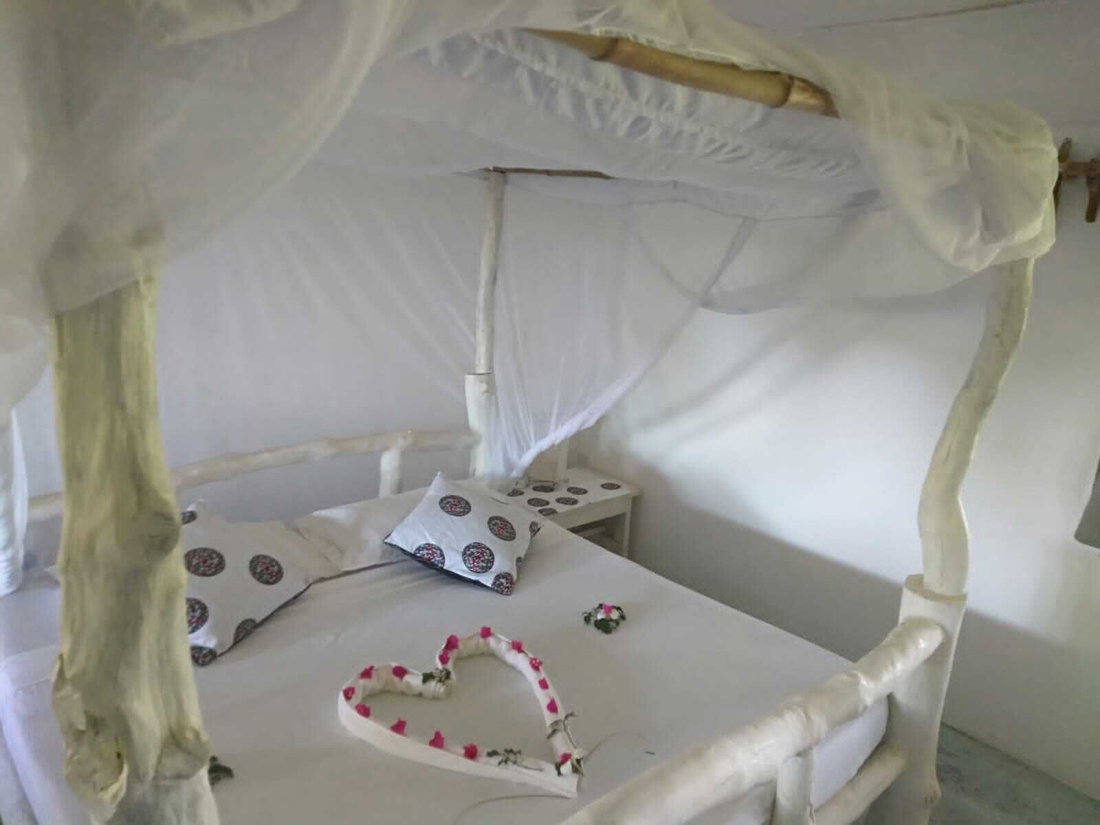 A bed with a canopy, a bedside table, and a heart-shaped decoration on the bed.