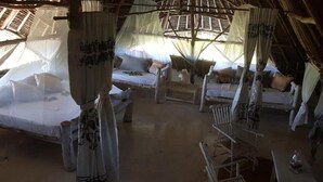 A room with two beds, each with a canopy, a small table, and a chair. - Safina Beach House (Watamu)