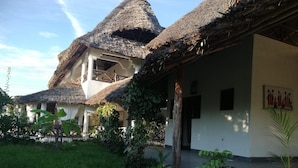 A traditional house with thatched roofs and a garden area. - Safina Beach House (Watamu)