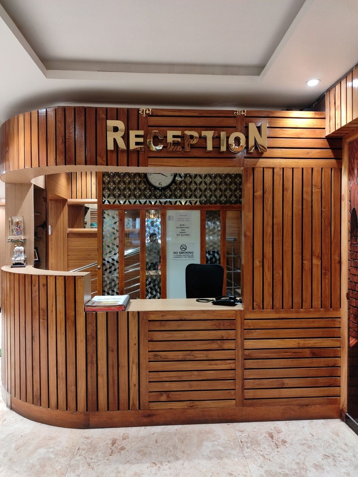 A reception desk with a wooden design, a clock, and a sign indicating no smoking.