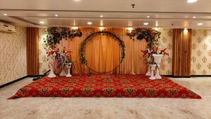 Eine Bühne mit rotem Teppich, Blumenschmuck und einem Holzhintergrund.