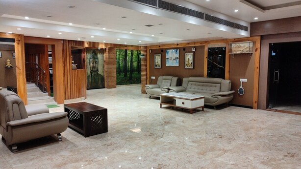 Eine großzügige Lobby mit Marmorboden, einer Treppe, einer Buddha-Statue und einer Sitzecke mit Sofas und einem Couchtisch.