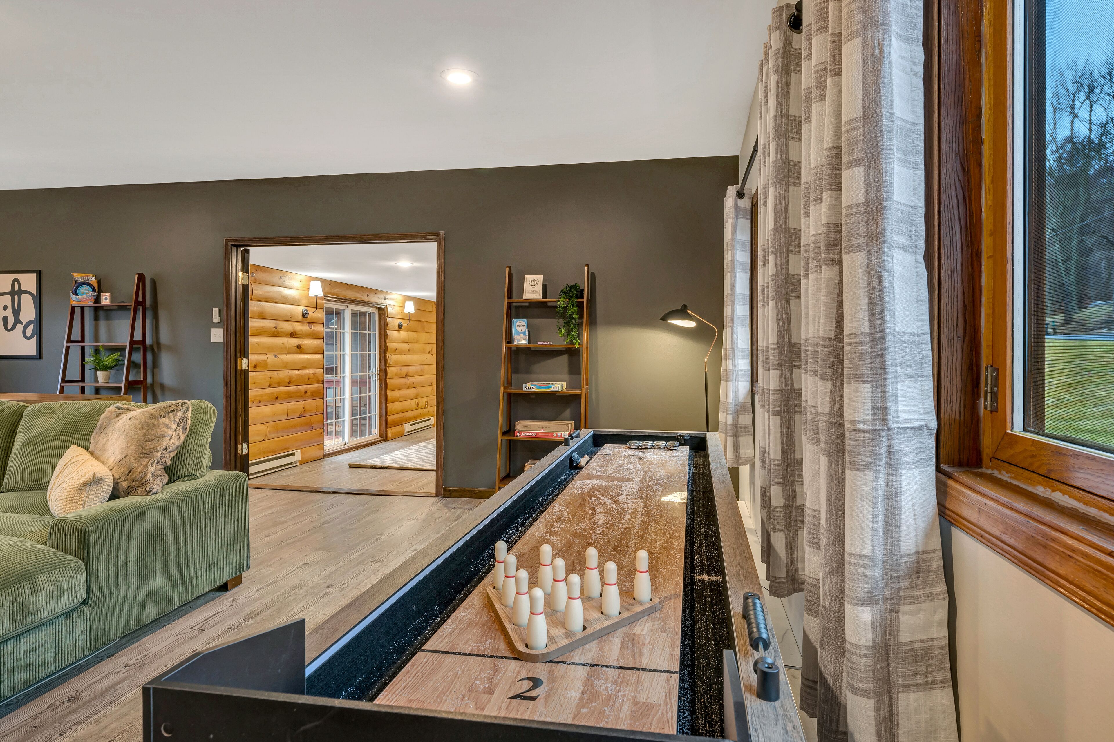 A room with a pool table, a green sofa, and a wooden door leading to another room.