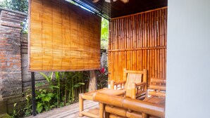 A bamboo-framed outdoor seating area with a brick wall and greenery. - Sandora Homestay by Supala (Ubud)