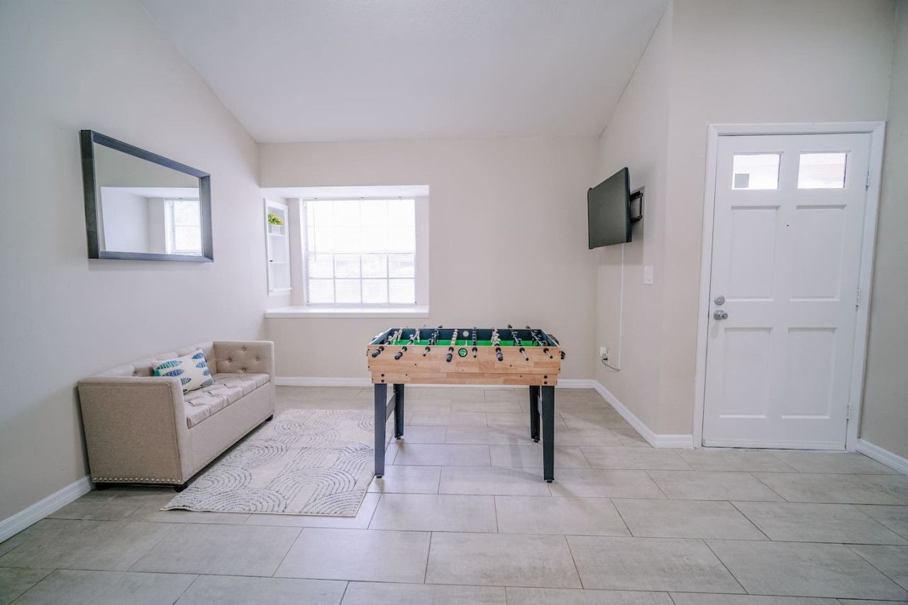 A room with a foosball table, a sofa, a television, and a door.