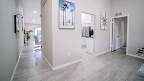 A spacious hallway with a kitchen area, a dining area, and a door leading to another room.
