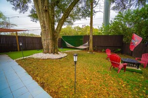 Ein Garten mit einer Hängematte, Terrassenmöbeln und einer Flagge.