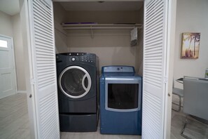 Ein Waschraum mit Waschmaschine und Trockner, einem Wäscheständer und einem Bild an der Wand.