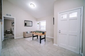 Una habitación amplia con mesa de fútbol, una puerta y un ventanal.