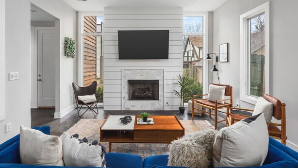 Una sala de estar moderna con chimenea, televisor de pantalla plana y un sofá azul.