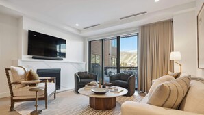 A modern living room with a fireplace, comfortable seating, a flat-screen TV, and large windows offering a view of the outdoors. - Frontgate 206 - 2 Bedroom Residence (Avon)