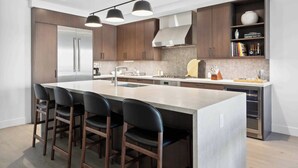 A modern kitchen with a central island, bar stools, and built-in appliances. - Frontgate 206 - 2 Bedroom Residence (Avon)