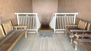 A narrow hallway with wooden benches on either side and a white railing with decorative elements. - Hotel O Hidayah Homestay Syariah (Sidoarjo)