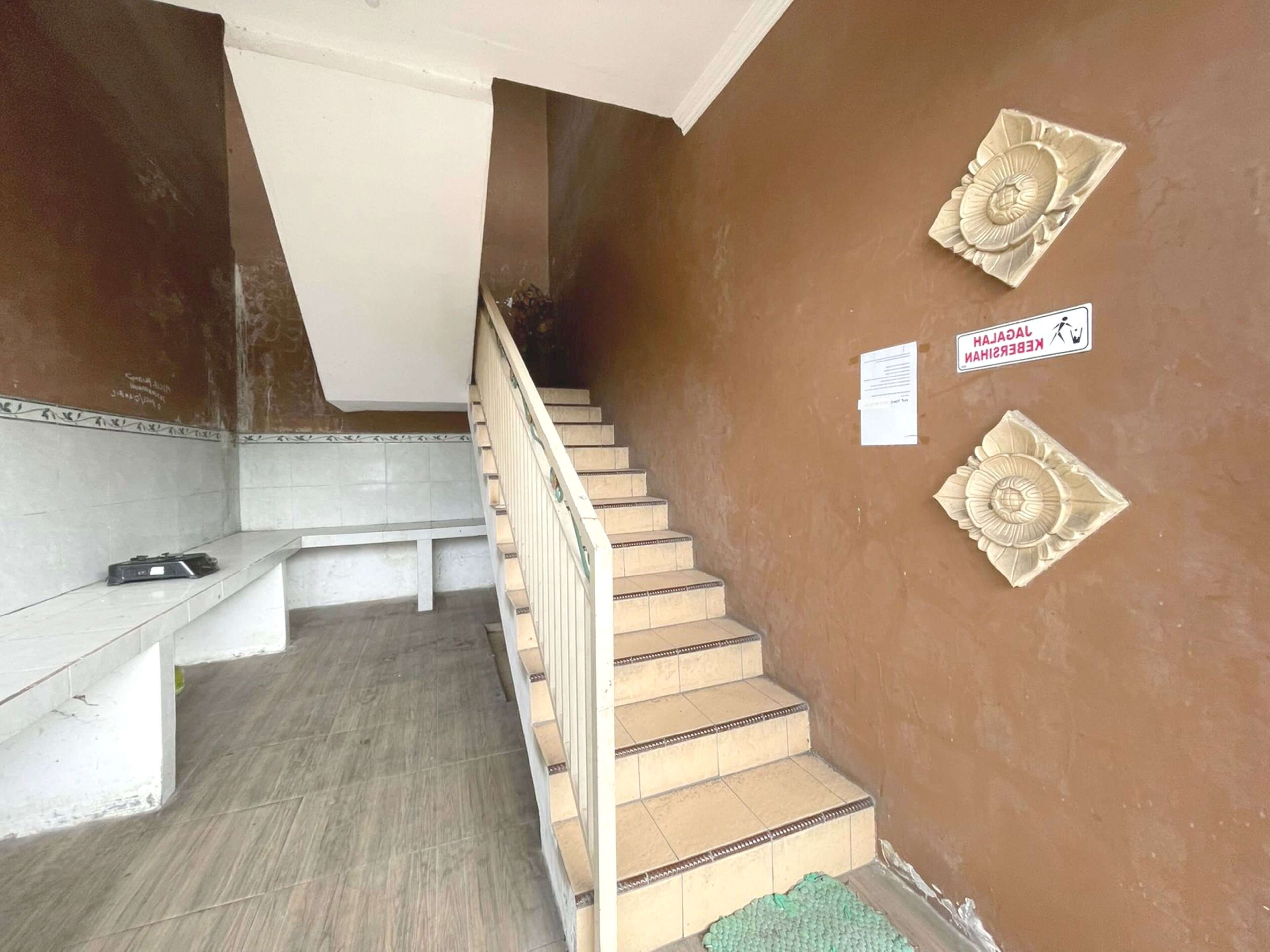 A staircase with a handrail, a bench, and a green mat at the bottom.