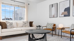 Una sala moderna con sofá, sillones, una mesa de centro y obras de arte en la pared.