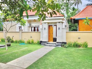 A two-story house with a red-tiled roof, a front entrance with a wooden door, and a well-maintained lawn. - Belvilla Serene Picturesque Near Monkey ForestNearPura Tirta Tawar (Mambal)