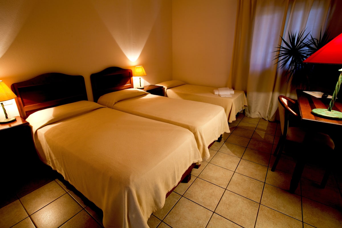 A hotel room with two beds, a desk, and a chair.