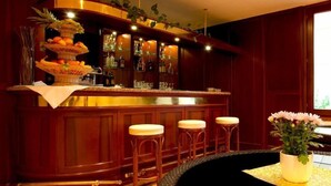 Un coin bar avec un comptoir en bois, trois tabourets et une plante décorative.