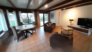 Ein großzügiger Wohnbereich mit Esstisch, Sofas, Fernseher und Kamin.