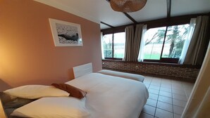Ein Schlafzimmer mit einem großen Bett, einem Kopfteil, einem Fenster mit Vorhängen und einer Ziegelwand.