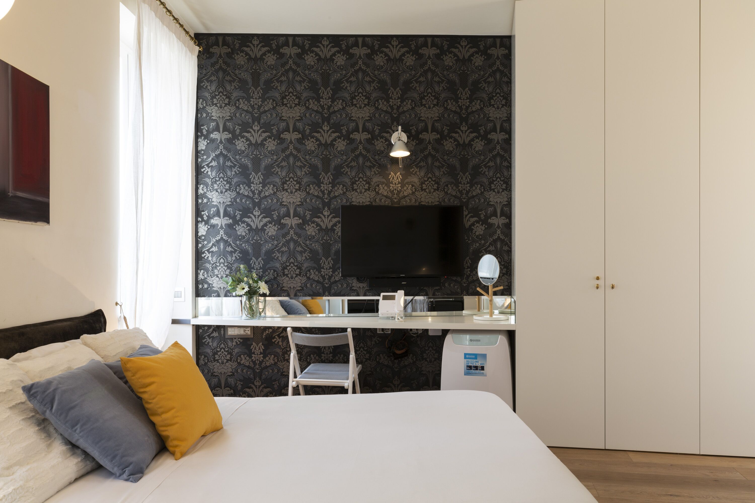 Une chambre à coucher comprenant un lit, une table de chevet, une chaise, un bureau, une télévision et une armoire.