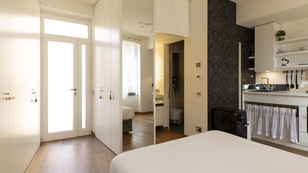 Un dormitorio moderno con una cama grande, baño privado y zona de kitchenette.