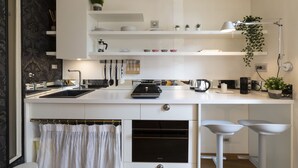 Una cocina moderna con armarios blancos, una estufa negra y una encimera con hervidor y cafetera.