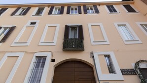 Fachada de edificio con varias ventanas, algunas con contraventanas, y una entrada central en arco.