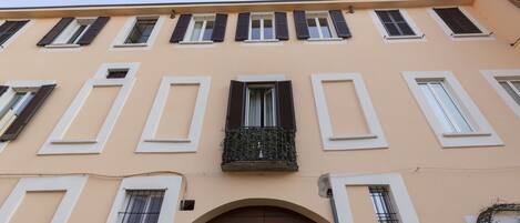A building facade with multiple windows, some with shutters, and a central arched entrance.
