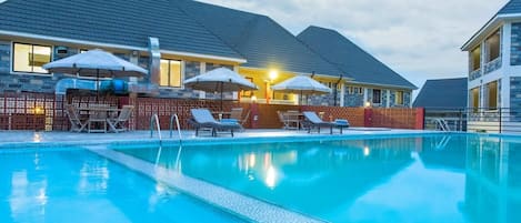 Una piscina al aire libre, sillones reclinables de piscina