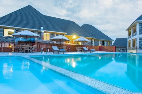 Una piscina al aire libre, sillones reclinables de piscina