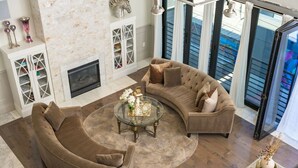 Una sala de estar moderna con un sofá curvo, una mesa de centro de vidrio y una chimenea.