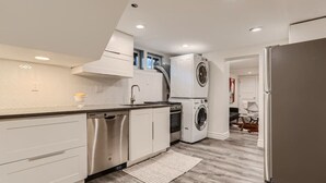 A modern kitchen with white cabinetry, stainless steel appliances, and a built-in washer and dryer. - Hilltop I Cherry Creek I Guest suite I Museums (Denver)