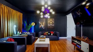 A modern living room with a dark blue sofa, a white coffee table, and a ceiling light fixture. - Insta-Worthy 5BR Home I Pet Friendly  I Firepit (Denver)